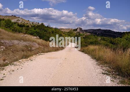 Ländliche Schotterstraße nach Kljuc und schöner bewölkter Himmel, Gacko, Bosnien und Herzegowina Stockfoto