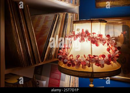 Details einer alten dekorativen Lampe neben einem Schrank mit Schallplatten, eine persönliche Sammlung von Musikalben in einem Wohnzimmer. Stockfoto