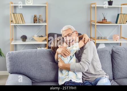 Großvater sitzt auf dem Sofa und umarmt seinen Enkel, Nahaufnahme Stockfoto