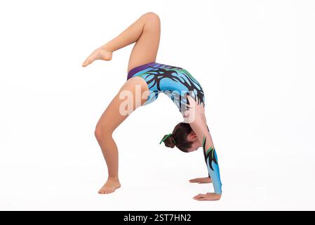 Junge akrobatische Turnerin, die Gymnastikübungen durchführt, isoliert auf weißem Hintergrund. Sport, Wettkampf und gesundes Leben bei Jugendlichen Stockfoto