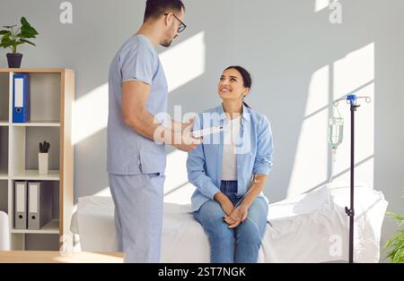 Männlicher Arzt oder Krankenschwester unterstützt junge Frauen, die eine intravenöse Vitamintherapie erhalten Stockfoto