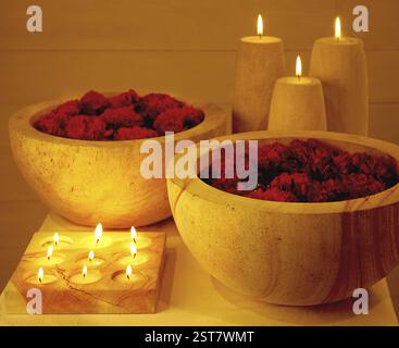 Rote Blumen in Holzschale und Kerzen, intimes romantisches Thema Stockfoto