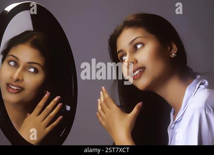 Südasiatische Indianerin kämmt ihre Haare mit Kamm vor einem Spiegel Stockfoto