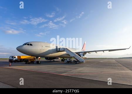 Passagierflugzeug mit breitem Körper und Flugzeugtreppen am Flughafen. Ein Flugzeugtanker betankt ein Flugzeug Stockfoto