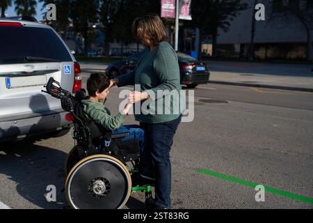Mutter hilft einem behinderten Sohn, der im Rollstuhl aus dem Auto steigt Stockfoto