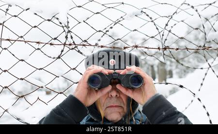 Blick durch ein Fernglas, alte DDR-Garde Hut Mann Stockfoto
