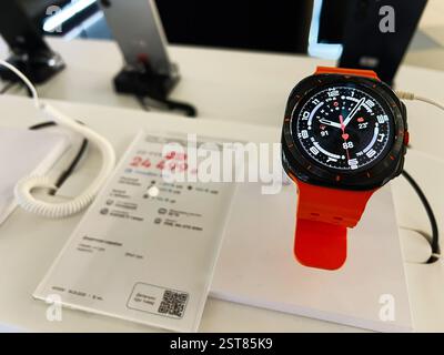 Lviv, Ukraine - 16. Februar 2025: Moderne Samsung Smartwatch mit leuchtenden orangen Bands an einem Ladentisch Stockfoto
