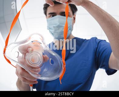 Medizinisches Fachpersonal in Peelings und Schutzmaske bereitet eine Atemmaske mit Sauerstoff vor und gibt sie einem Patienten mit Atemproblemen, Nahaufnahme Stockfoto
