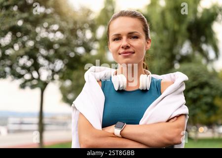 Porträt einer jungen Frau mit Kopfhörern um den Hals, die draußen laufen Stockfoto