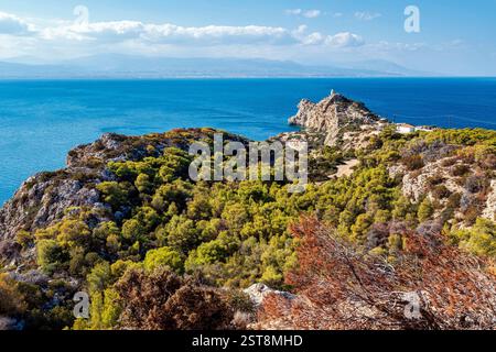 Eine malerische Küstenlandschaft mit üppigen grünen Hügeln, felsigen Klippen und Melagavi Lighthouse auf einem zerklüfteten Landzunge mit Blick auf den korinthischen Gül Stockfoto