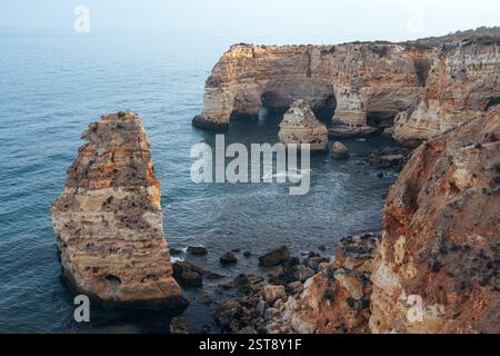 Klippen, Felsformationen und Naturbögen am Strand La Marina bei Sonnenuntergang in der Algarve in der Nähe der Städte Albufeira und Portimao. Portugal. Stockfoto