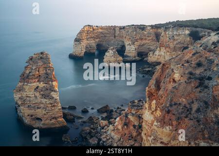Klippen, Felsformationen und Naturbögen am Strand La Marina bei Sonnenuntergang in der Algarve in der Nähe der Städte Albufeira und Portimao. Portugal. Stockfoto