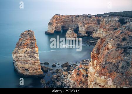 Klippen, Felsformationen und Naturbögen am Strand La Marina bei Sonnenuntergang in der Algarve in der Nähe der Städte Albufeira und Portimao. Portugal. Stockfoto