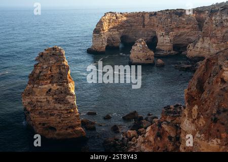 Klippen, Felsformationen und Naturbögen am Strand La Marina bei Sonnenuntergang in der Algarve in der Nähe der Städte Albufeira und Portimao. Portugal. Stockfoto