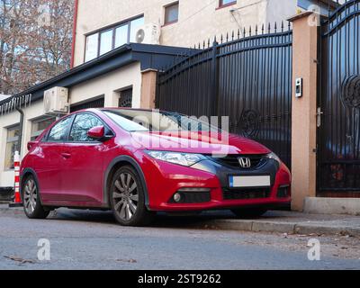 Bukarest, Rumänien – 9. Januar 2025: Roter Honda Civic parkt auf der Straße vor dem Haus. Nahansicht der Vorderseite. Stockfoto