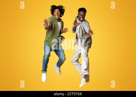 Zwei Fröhliche, Emotionale Afroamerikanische Jungs Springen Über Beigen Studiohintergrund Stockfoto