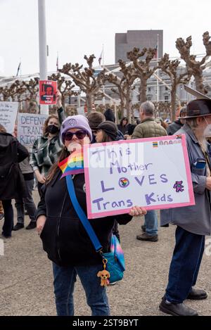 San Francisco, Kalifornien, USA, 17. Februar 2025. Eine Frau hält ein Schild mit der Aufschrift „This Mother Loves Trans Kids“ mit einer Regenbogenfahne beim Protest gegen Trump „No Kings Day“ des Präsidenten im Rathaus von San Francisco. Shelly Rivoli/Alamy Stockfoto