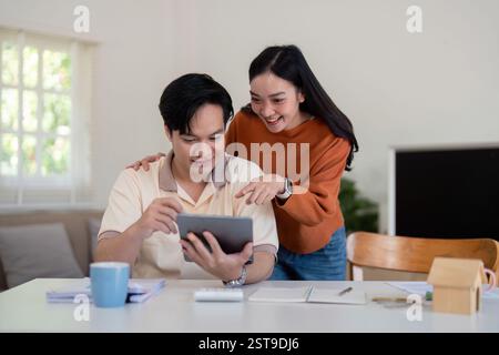 Ein Paar diskutiert aufgeregt über seine Finanzpläne, während er sich ein Tablet ansieht. Stockfoto