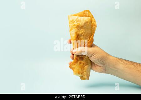 Döner Kebab, Shawarma in Pita Cutaway in männlicher Hand auf hellblauem Hintergrund. Hellblaue Hintergrundfarbe. Stockfoto