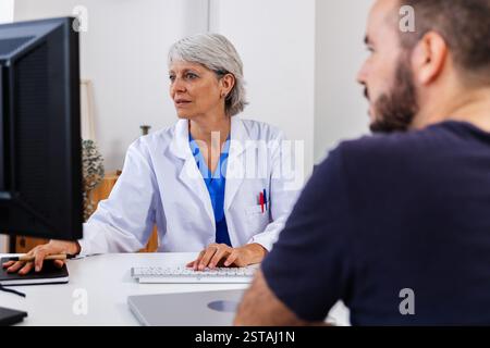 Weibliche Ärztin, die dem Patienten Informationen auf dem Computer zeigt Stockfoto