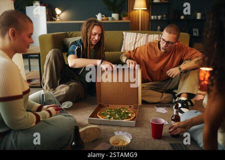 Genießen Sie Pizza mit Freunden in gemütlichem Wohnzimmer Stockfoto