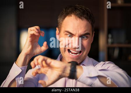 Ein junger wütender bärtiger, ernsthafter beschäftigter Mann schaut auf seine Uhr und überprüft die Zeit auf seinen Armbanduhren, die zu Hause im Sessel sitzen. Er beeilt sich, in einem Hurr Stockfoto