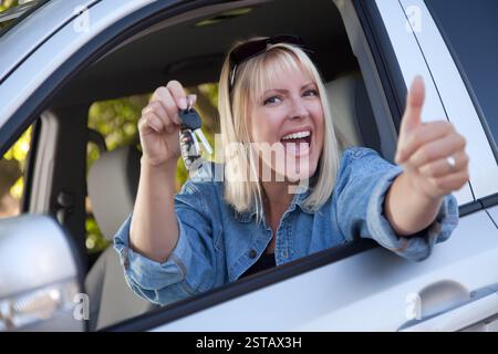 Attraktive glückliche Frau In Neuwagen mit Schlüsseln. Stockfoto