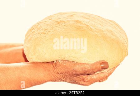 Hände, die einen fertigen, sauberen Teig halten. Hände halten den Teig bereit zum Backen. Alte Frauenhände verarbeiten den Teig zu Weizenbrot Stockfoto