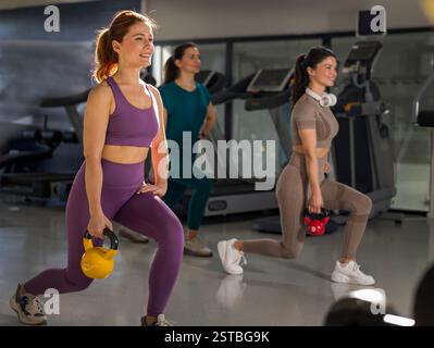 Gruppe junger hübscher Frauen, die mit Kettlebells im Indoor Gym trainieren. Sport und Gesundheitskonzept Stockfoto
