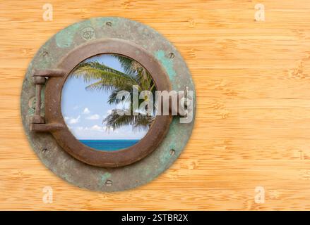 Antikes Bullauge mit Blick auf den tropischen Strand an der Bambuswand Stockfoto
