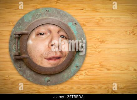 Antikes Bullauge an der Bambuswand mit Funky man, der durchschaut Stockfoto