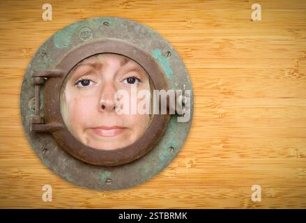 Antikes Bullauge an der Bambuswand mit Funky-Frau, die durchschaut Stockfoto