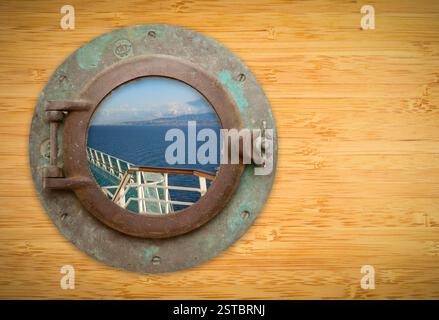 Antikes Bullauge auf Bambuswand mit Blick auf das Schiffs-Deck-Geländer und das Meer Stockfoto