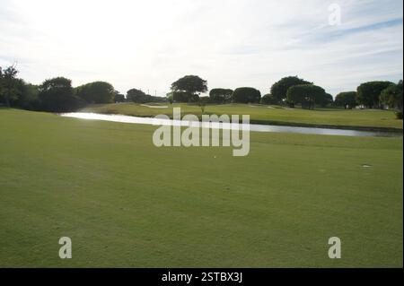 Ein malerischer Blick auf einen Golfplatz von Miami mit einem glitzernden Teich und alten Bäumen. Dieses friedliche Golfziel bietet ein anspruchsvolles Fairway mit einer Wat Stockfoto