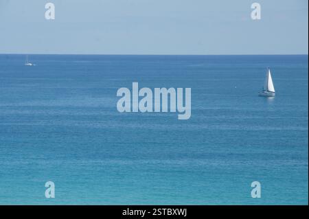 Ein winziges Segelboot durchquert den riesigen Ozean von Miami, der von der endlosen Weite des klaren blauen Himmels verzaubert wird. Freiheit erschließt sich auf dem offenen Wasser. Stockfoto