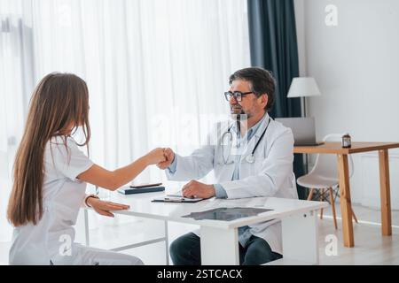 Erfolgreiche Vereinbarung zwischen Arzt und Kunde. Professionelle medizinische Fachkraft in weißem Mantel ist im Büro. Stockfoto