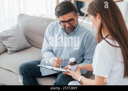 Verschreibungspflichtig und Pillen. Die professionelle Krankenschwester im weißen Mantel ist im Büro. Stockfoto