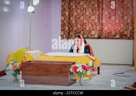 Eine fromme Frau liest das heilige Buch der Sikh, der Guru Granth Sahib, bei einem Tempelmorgendgottesdienst in South Richmond Hill, Queens, New York. Stockfoto