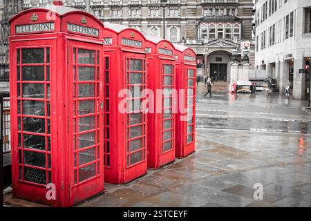 Rote Vintage-Londoner Telefonzellen, die entlang einer Straße in der Innenstadt von London aufgereiht sind. Foto in London, Großbritannien Stockfoto