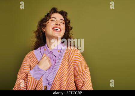 Eine junge und stilvolle Frau lächelt breit und strahlt Freude aus, während sie ein schickes Outfit trägt. Stockfoto