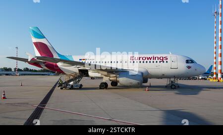 Eurowings Airbus A319 am Flughafen Düsseldorf während des Einstiegs auf einer Parkposition im Freien mit Transportbandwagen an der Ladeklappe Stockfoto