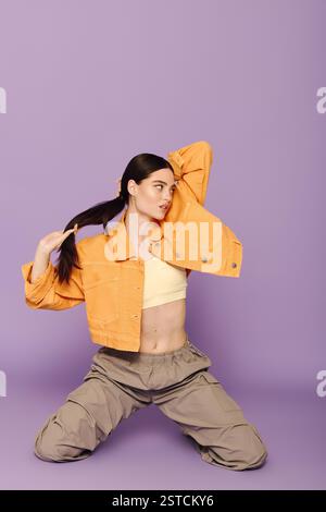 Die modische junge Frau präsentiert ihren stylischen Look mit einer verspielten Pose und leuchtenden Farben Stockfoto