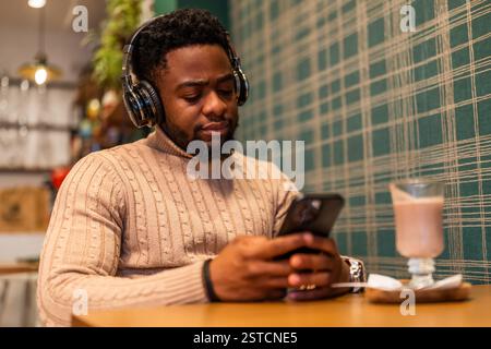 Freelancer hat eine Pause von der Arbeit, er benutzt ein Smartphone und trinkt heiße Schokolade in der Bar. Stockfoto
