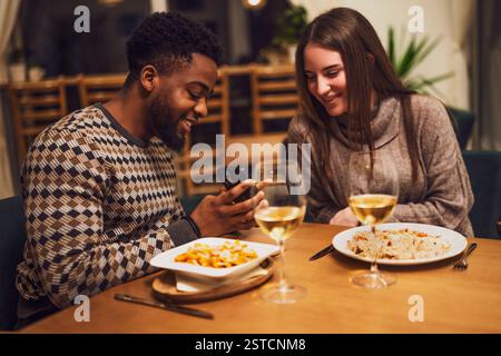 Zwei Freunde essen im Restaurant. Sie verwenden ein Smartphone. Stockfoto