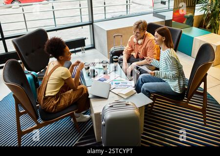 Drei Kollegen treffen sich an einem Tisch in einer Hotellobby, um ihre Pläne für eine Geschäftsreise zu besprechen. Stockfoto