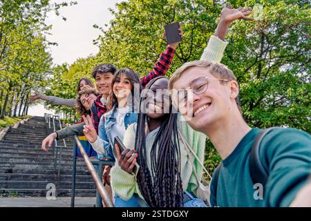 Eine vielfältige Gruppe von Schülern macht ein Selfie im Freien, lächelt und hat Spaß in einer natürlichen Umgebung. Stockfoto