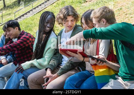 Eine vielfältige Gruppe von Studenten, die mit einem Tablet an einem Projekt arbeiten und Wissen und Kreativität im Freien austauschen. Stockfoto