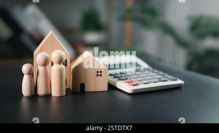 Das Hausmodell und der Mensch neben dem Rechner betonen Immobilien- und Finanzplanung, wobei Banken, Sparen und Investitionen klar dargestellt werden Stockfoto