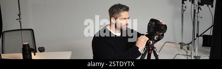 Eine engagierte Person richtet ihre Kameraausrüstung so ein, dass sie in einem Studio atemberaubende Bilder einfangen kann. Stockfoto