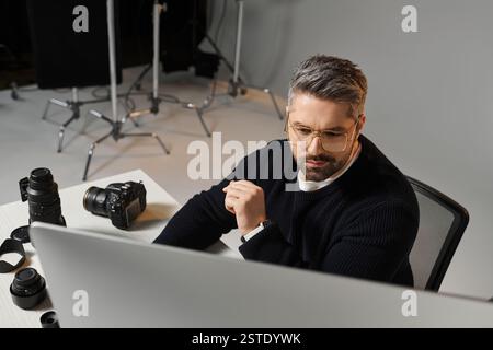 Ein Mann konzentriert sich tagsüber auf die Bearbeitung von Fotos in einer modernen Umgebung. Stockfoto